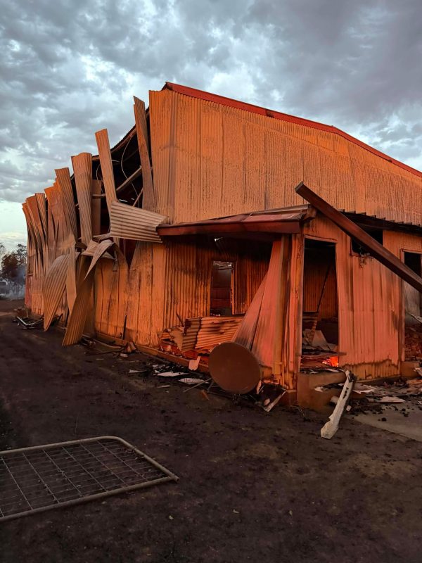 Fire-damaged buildings at Carranballac Recreation Reserve, with twisted corrugated iron and collapsed structures following the January 2026 bushfire.